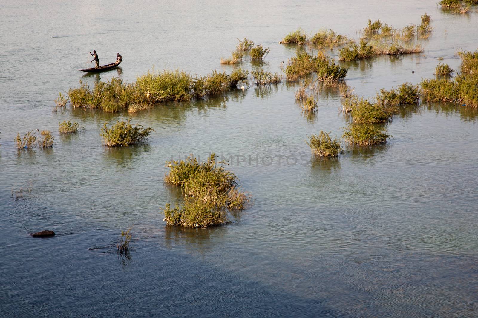 BAMAKO, MALI, JANUARY 7: Unidentified fisher man working in their boat on the Niger River in Bamako with the countryside in the background. Mali 2011
