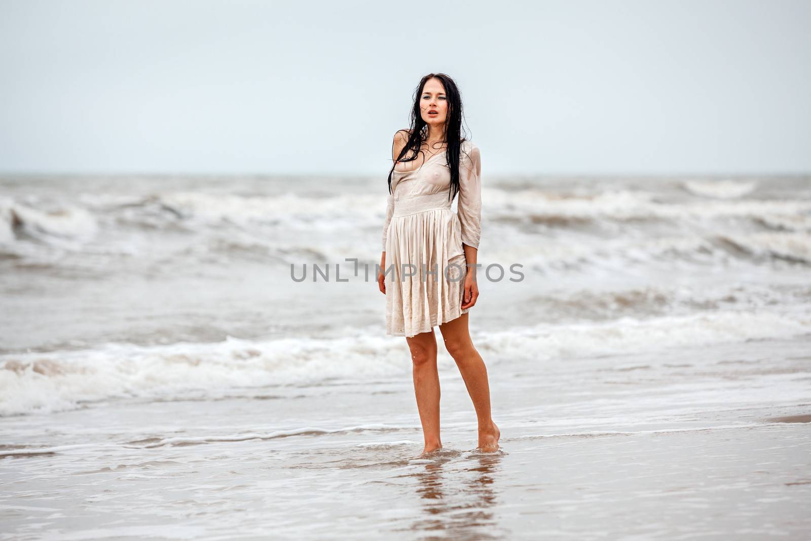 Beautiful young seminude woman in the cold sea waves