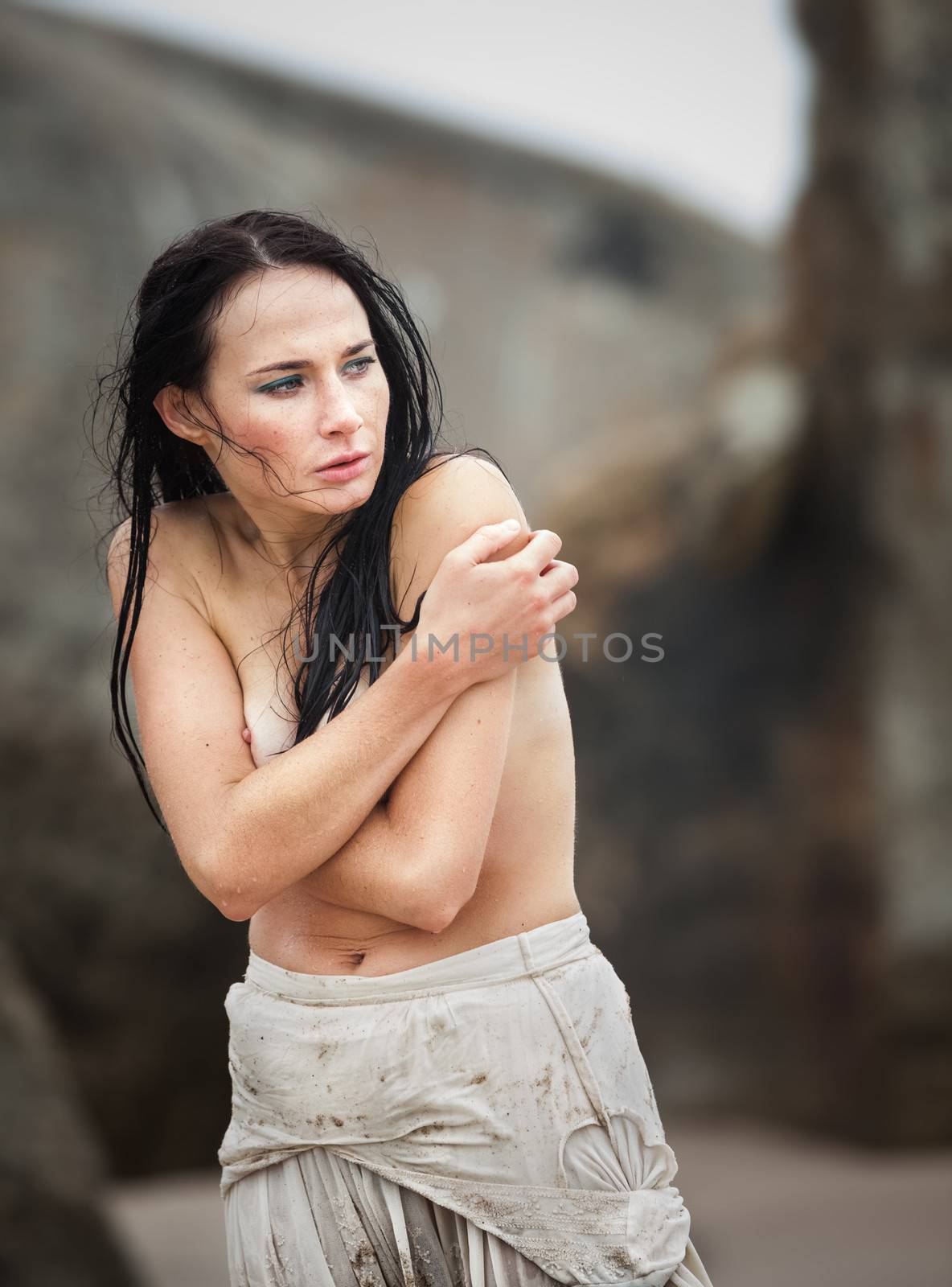 Cold day on sea beach. Frozen wet seminude young woman
