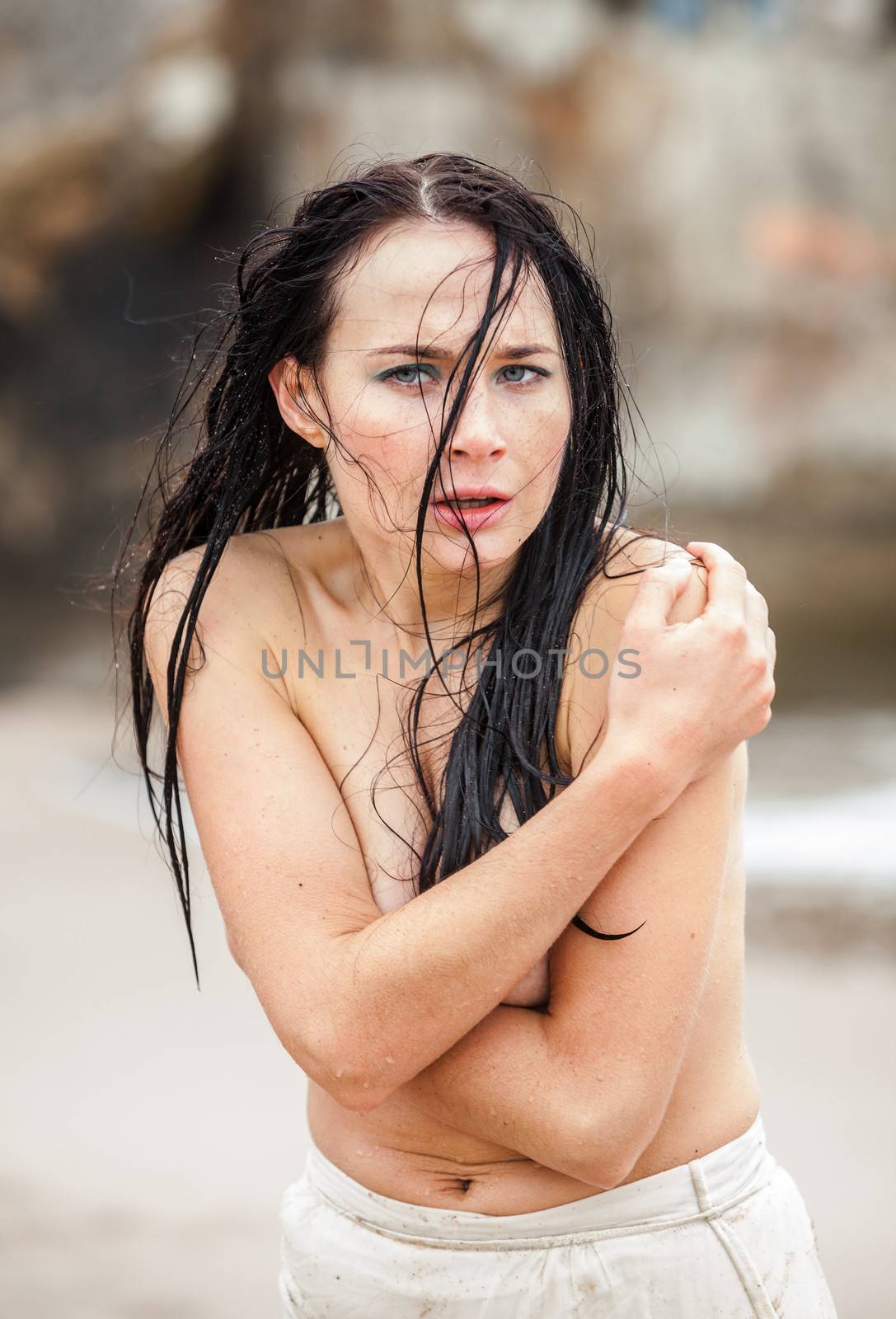 Frozen wet seminude young woman on cold sea beach