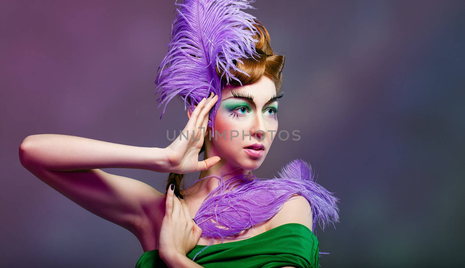 Attractive young girl with a fabulous makeup and feathers close-up portrait