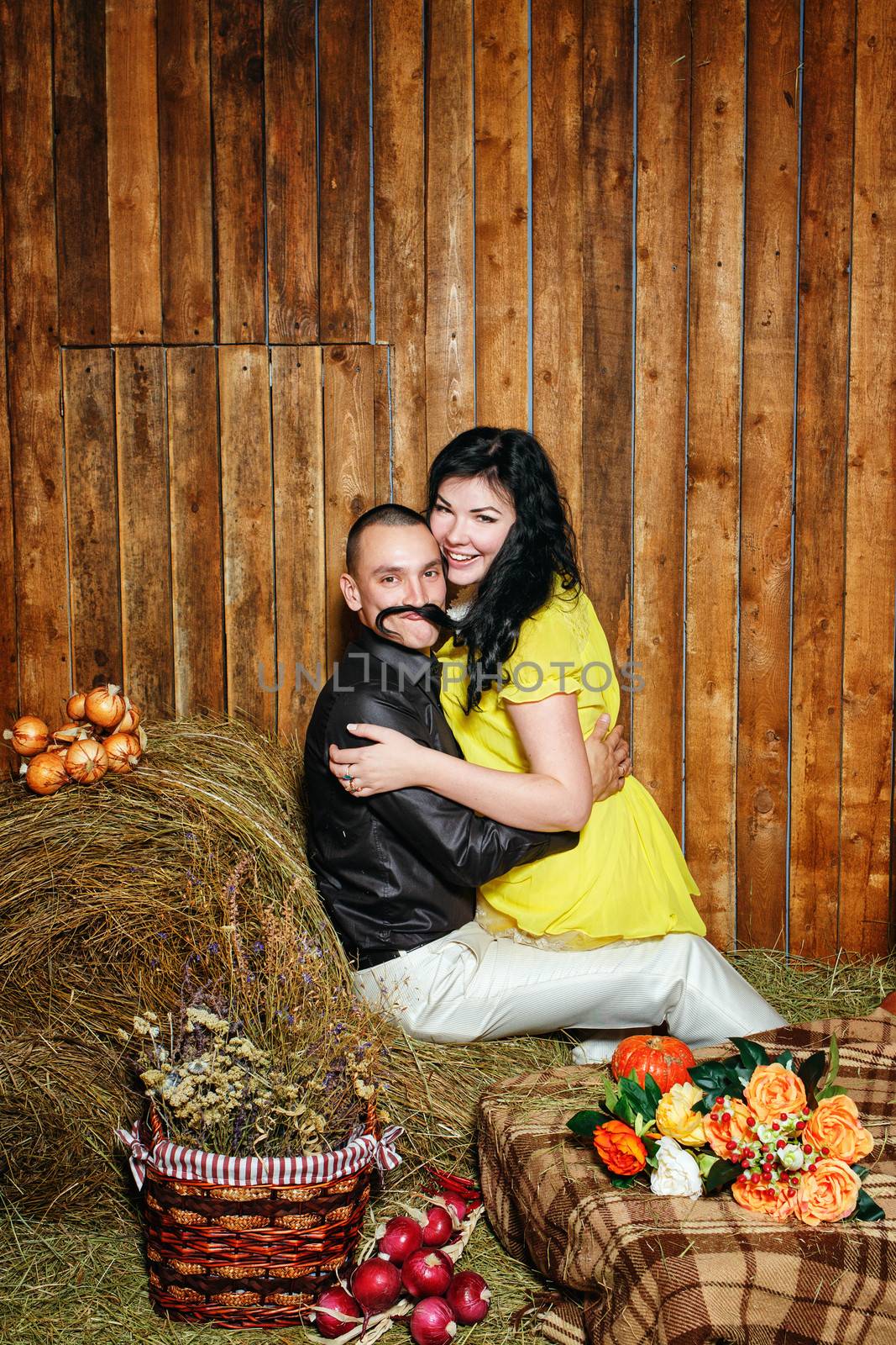 Young attractive couple playfully embrace in the hayloft in the village