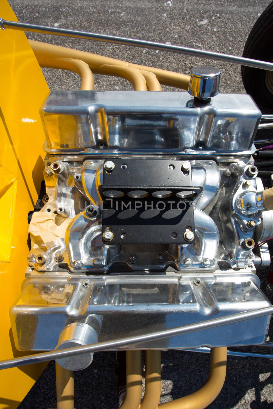 A hotrod engine with a supercharger and multiple air intakes mounted on a yellow frame at bonneville Salt Flats, Utah.