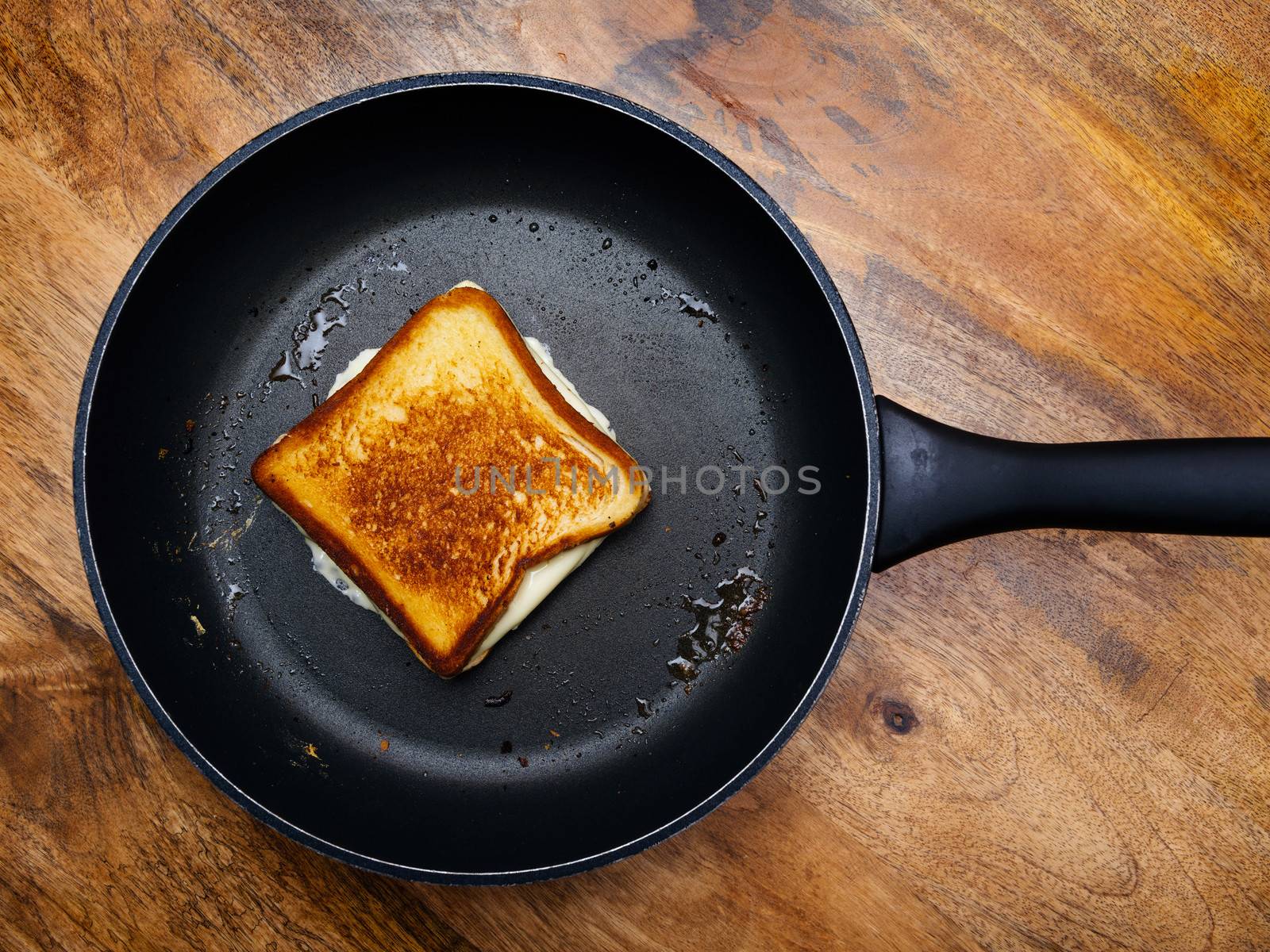 Photo of a grilled cheese sandwich cooking in a large frying pan.