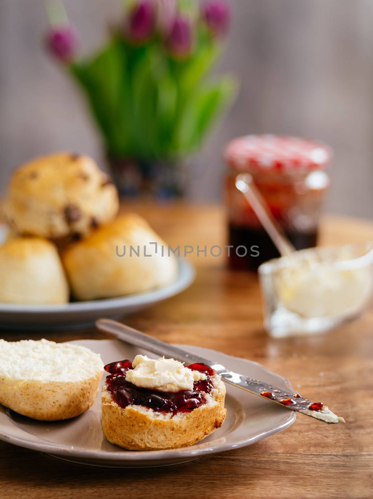 Photo of delicious scones on a plate with clotted cream and jam.
