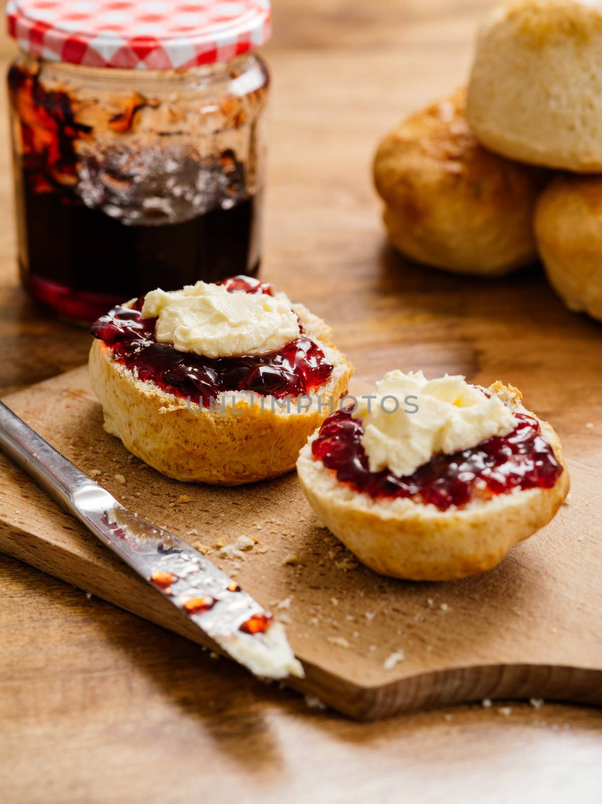 Two scones prepared with clotted cream and jam by sumners