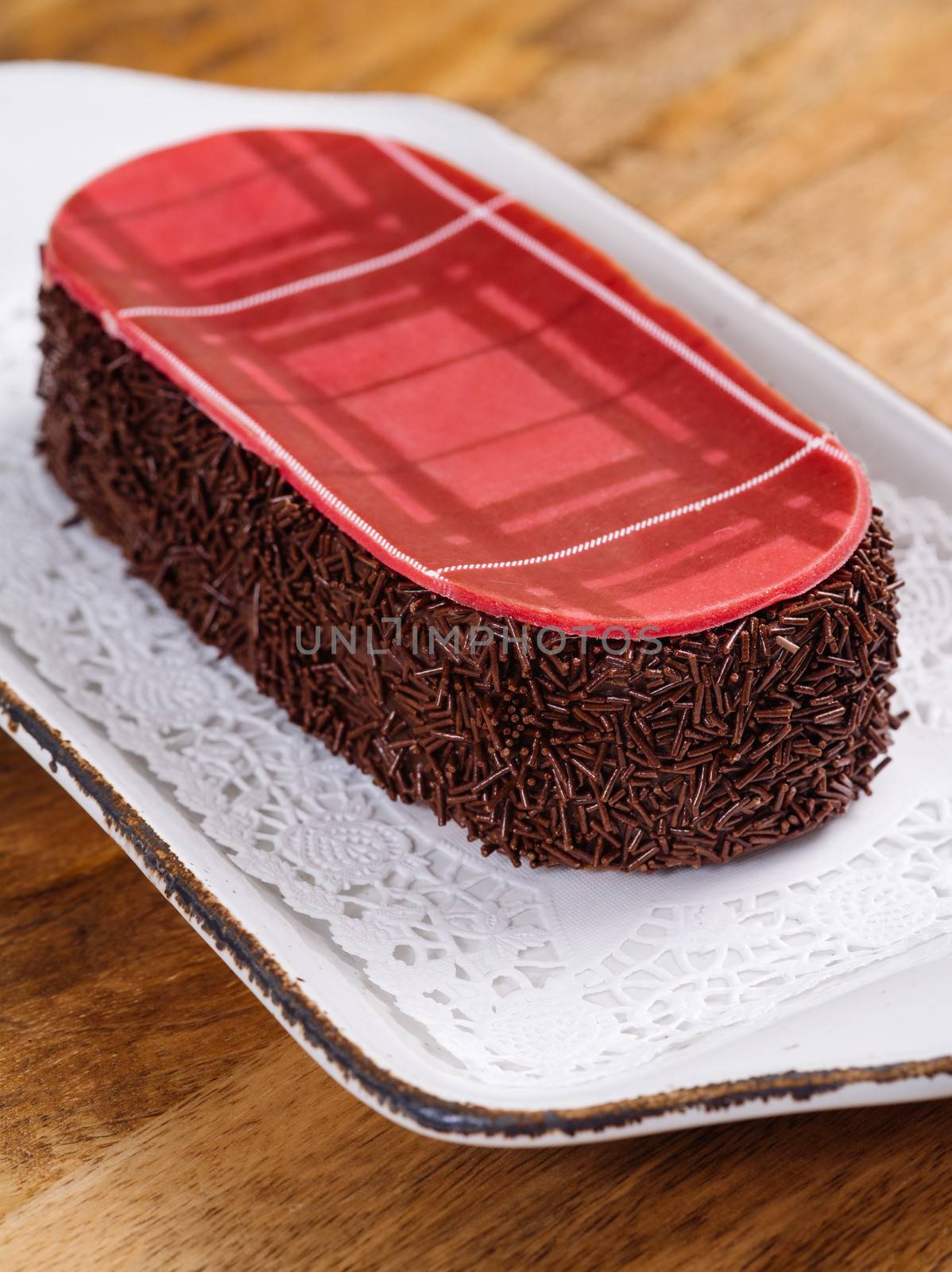 Photo of a Scottish whisky cake on a doily and plate on top of a wood table.
