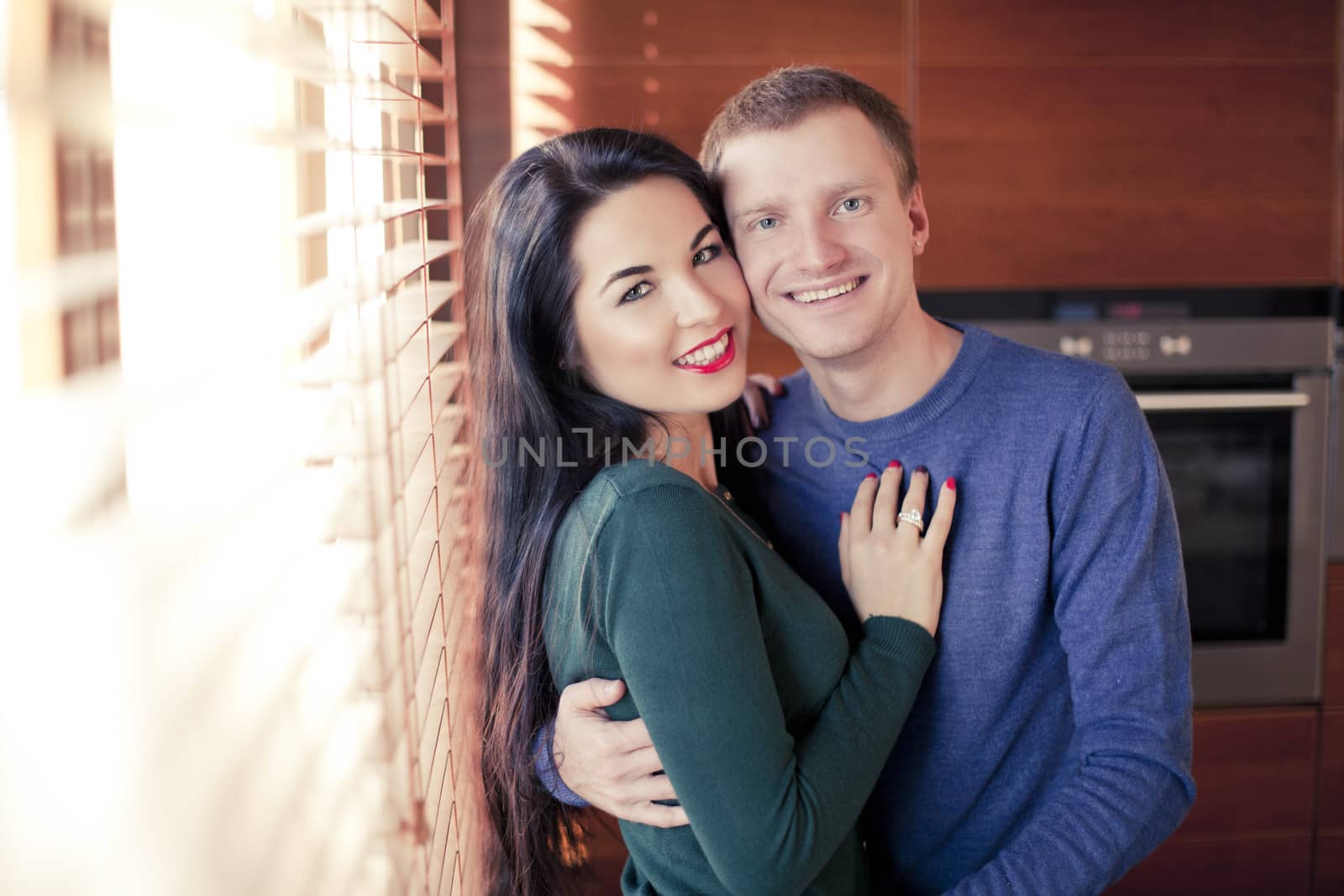 Young married couple in their house near the window louvers