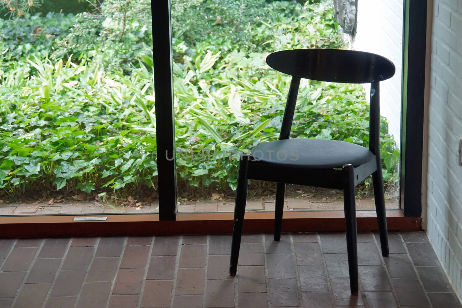 Classic design black wooden chair by a glass window                               