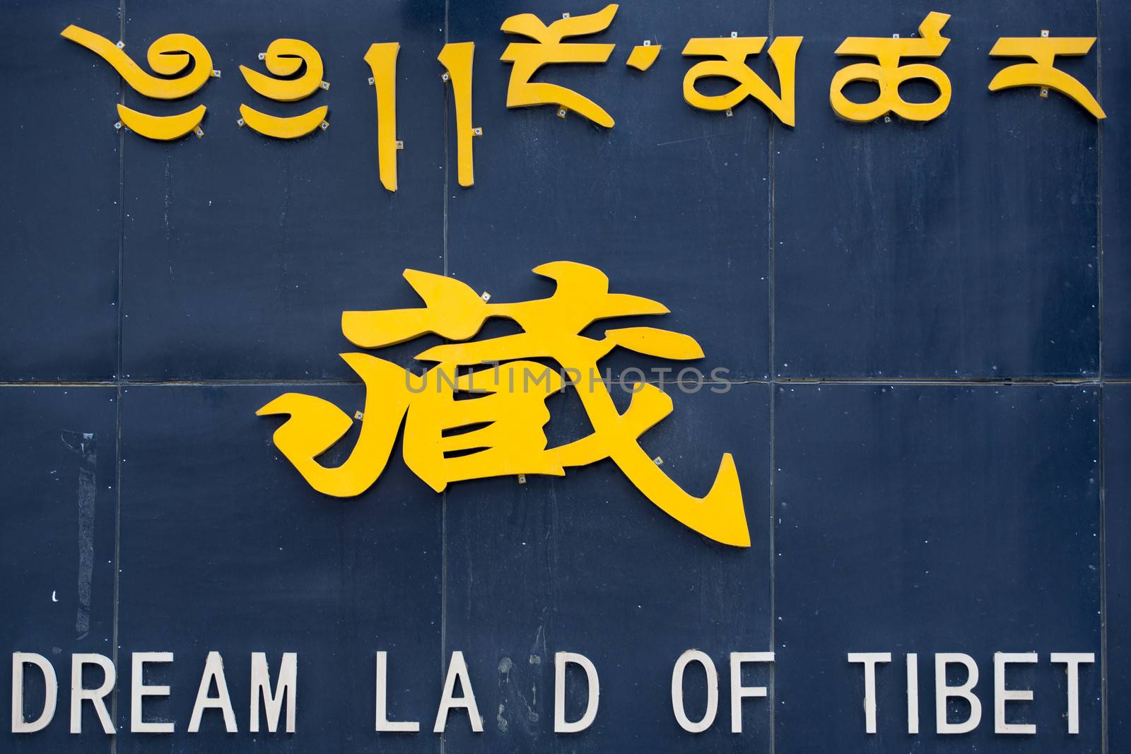 A broken sign saying: Dreamland of tibet in three languages, Tibetan, Chinese and English. Different letters are missing in the English version. Lhasa, Tibet.