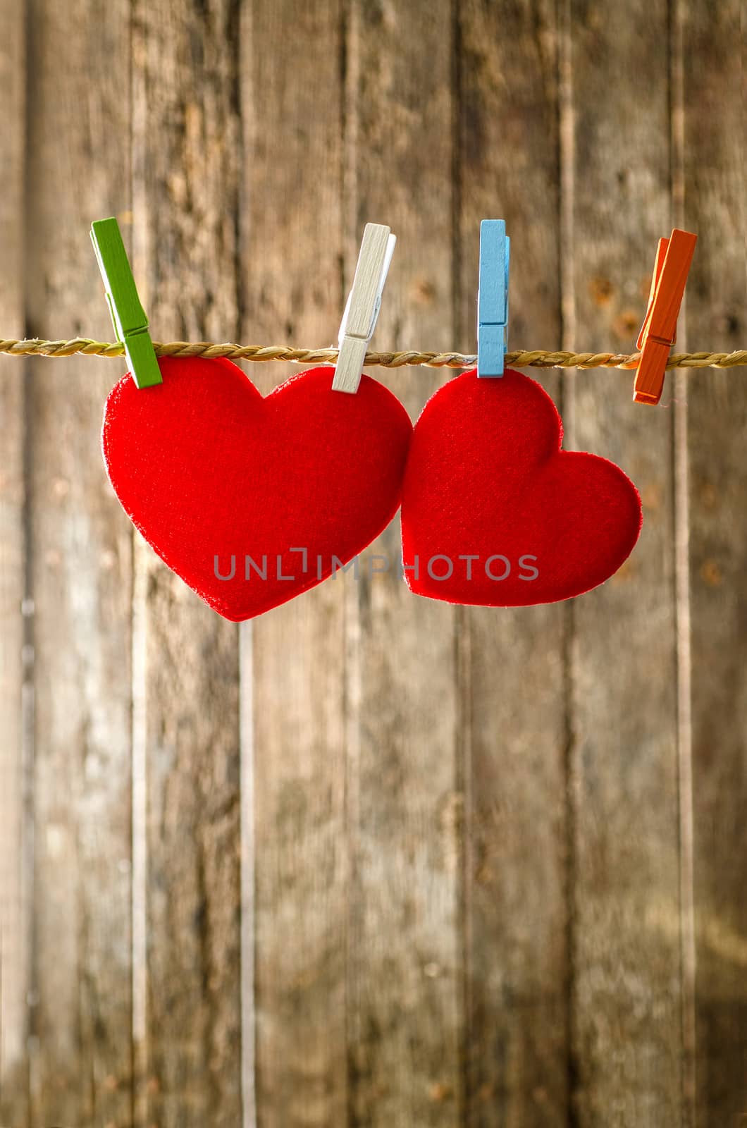 Cute big red heart hanging on the clothesline. On old wood background.