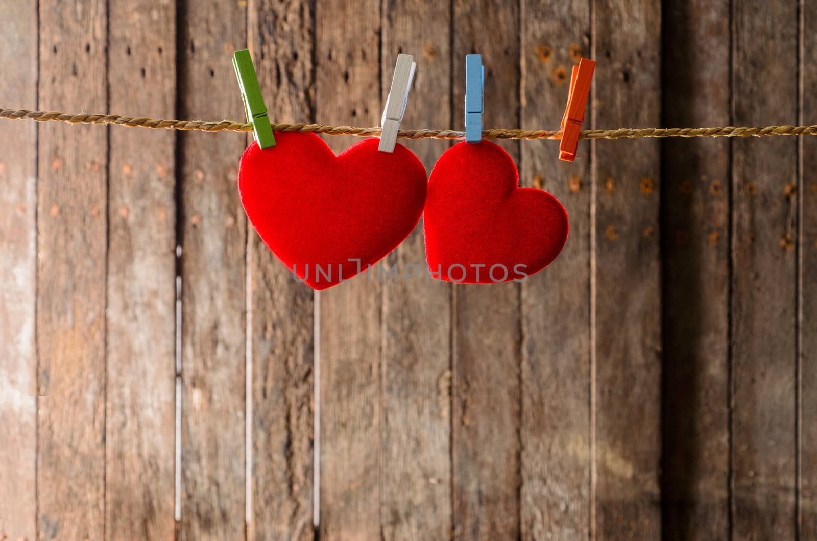 Cute big red heart hanging on the clothesline. On old wood background.