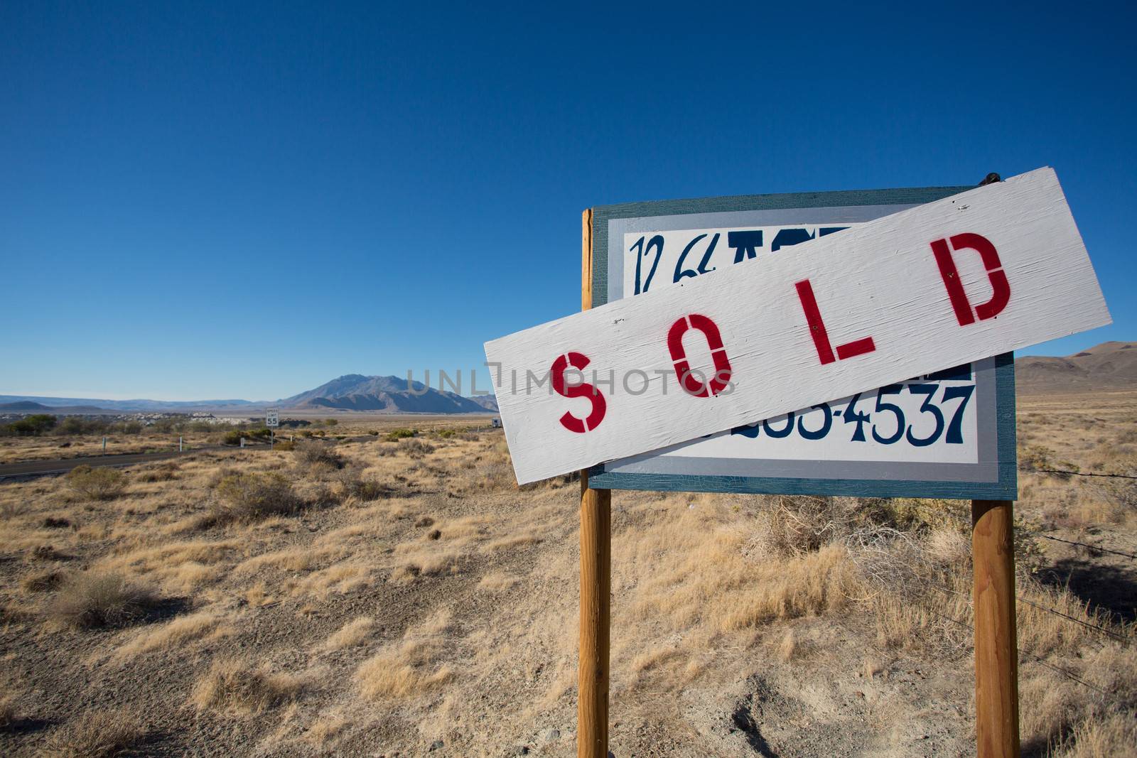 A sign for sale a plot in the middle of nowhere in Nevada states with a clear and blue sky in the background