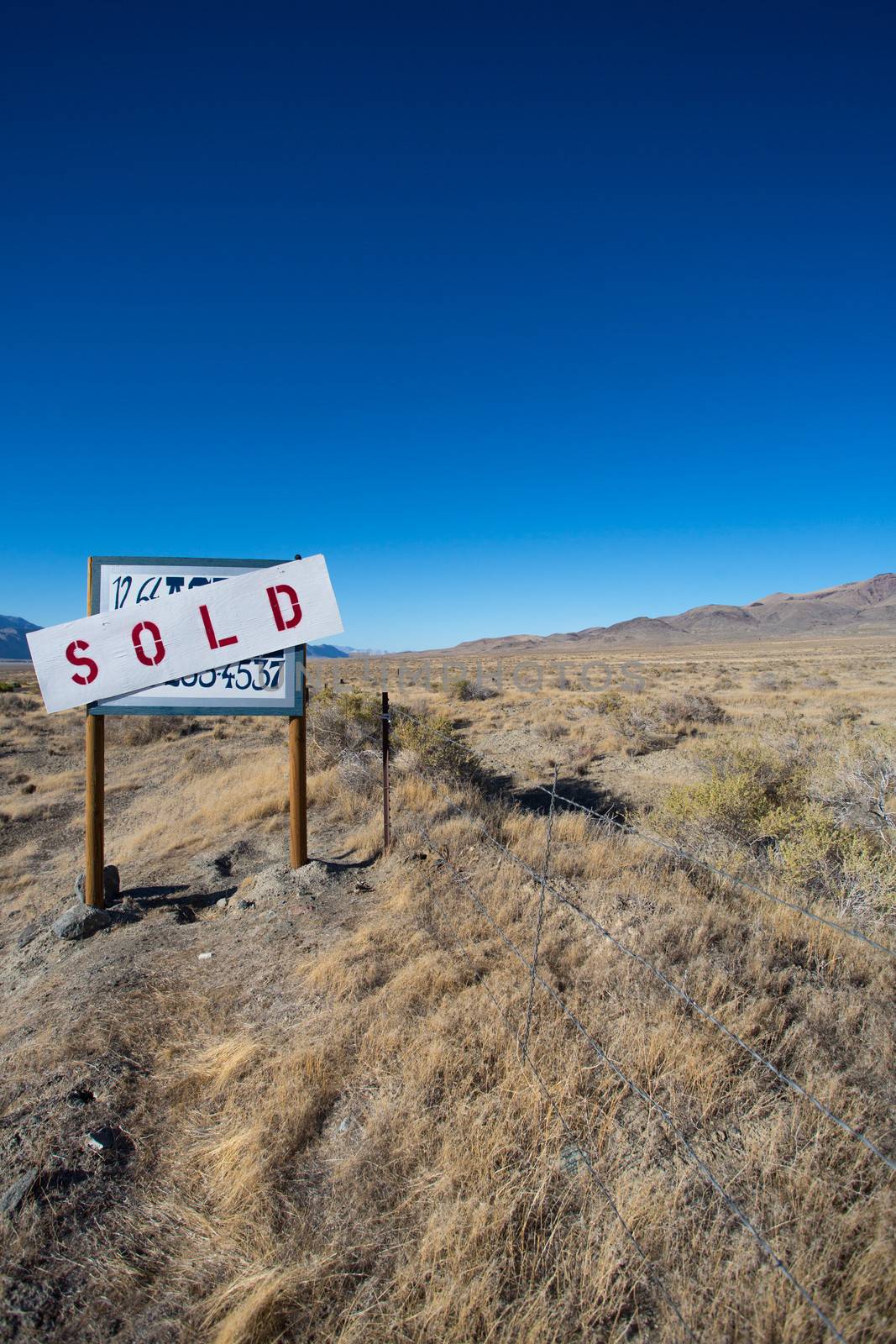 Sign board saying a farm land has been sold in the desert of nevada with a clear blue sky in the background, USA 2013.