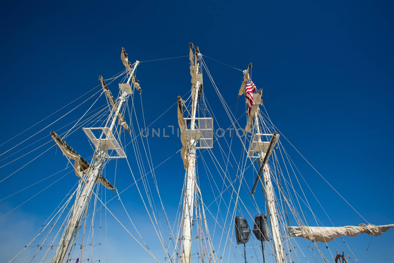 Details of a replica of a sailing boat with speakers and the American Flag with a clear sky in the background