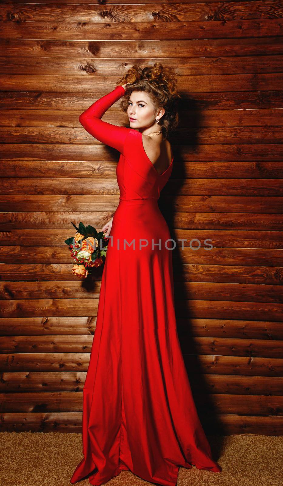 Lovely young girl in red dress holding bouquet of flowers