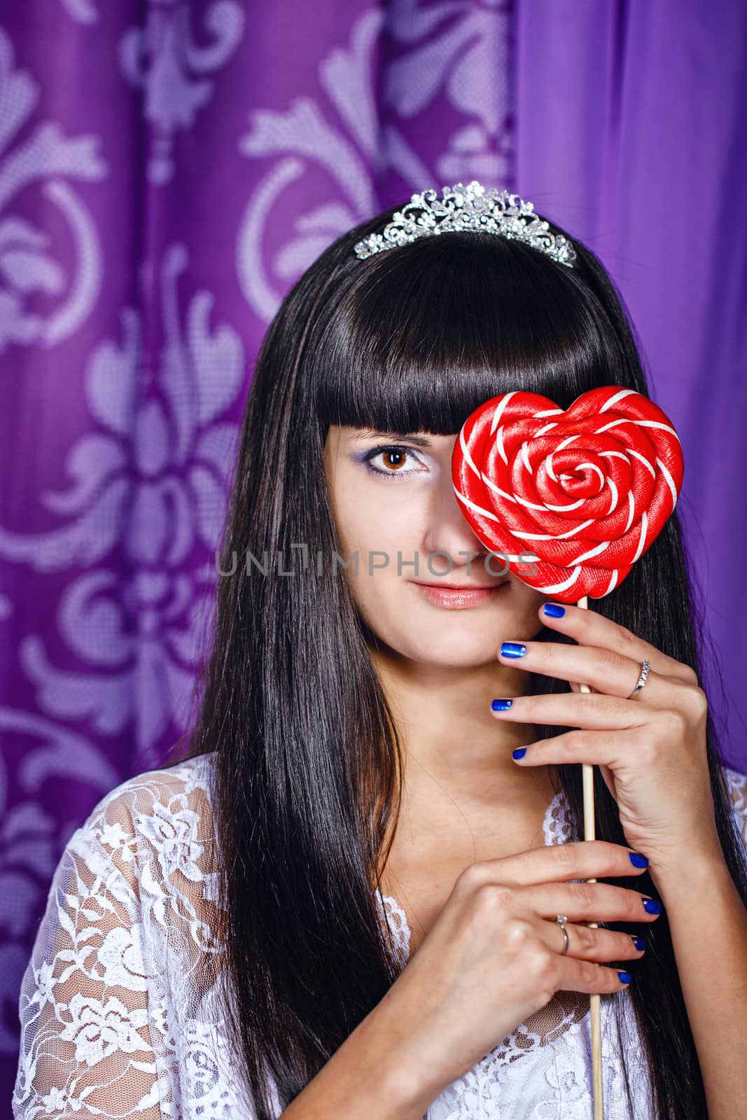 Attractive young brunette girl hiding behind big lollipop