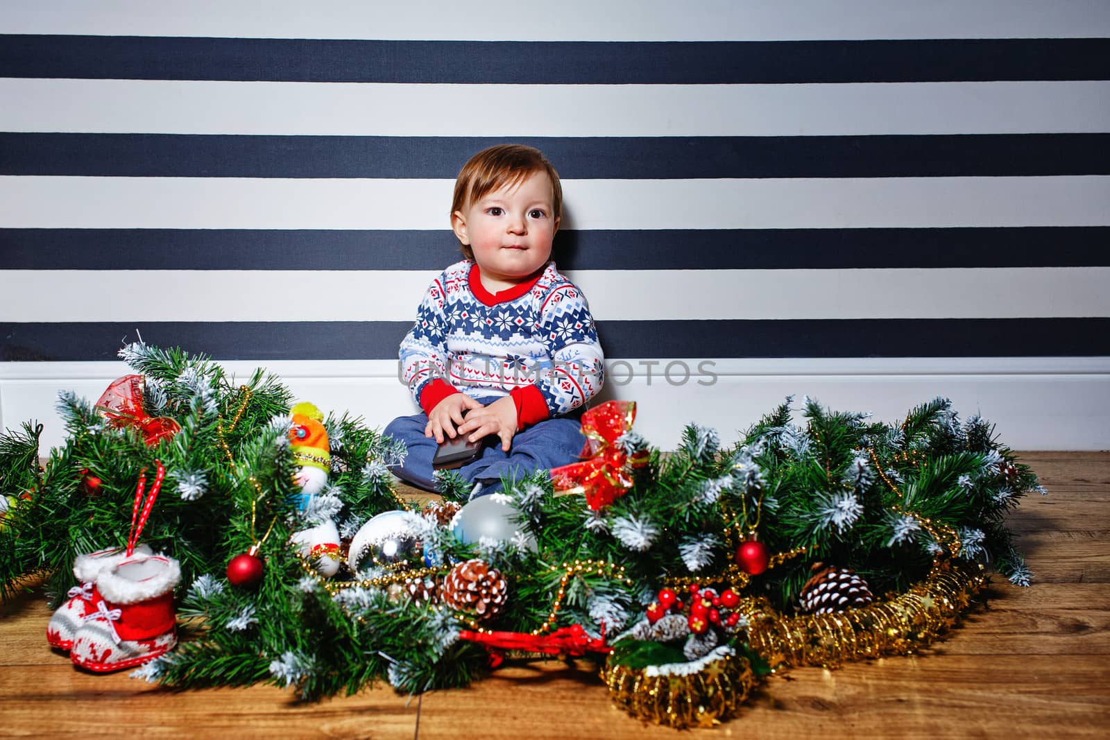 Little boy sitting on the floor surrounded by Christmas decorations