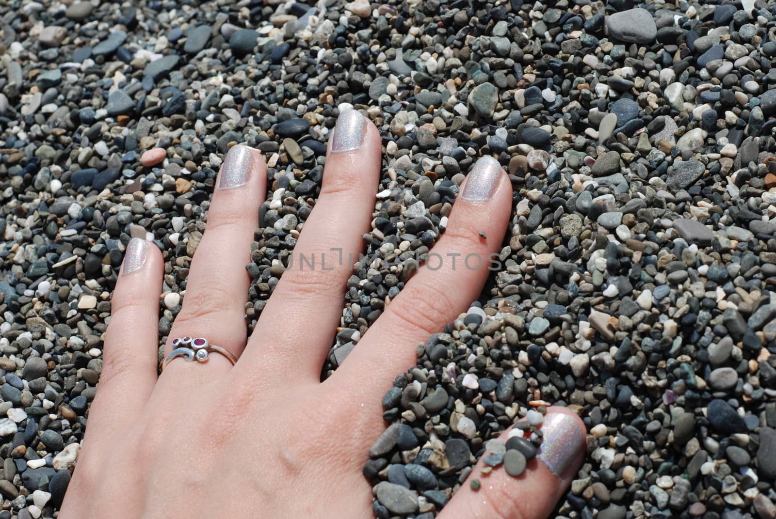 Girls hand with a ring on a finger in a pebble