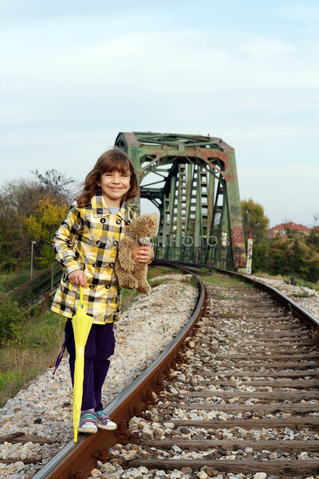 beautiful little girl standing on railroad