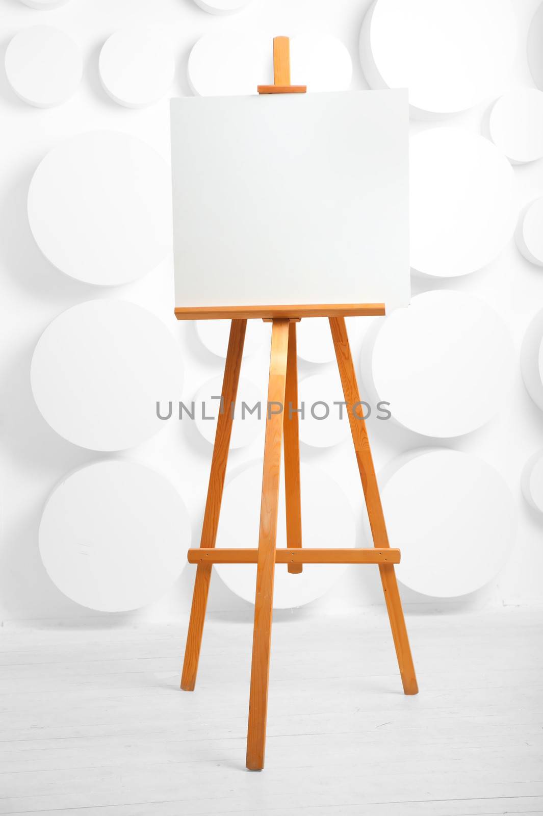 wooden easel with blank canvas in the studio by kosmsos111