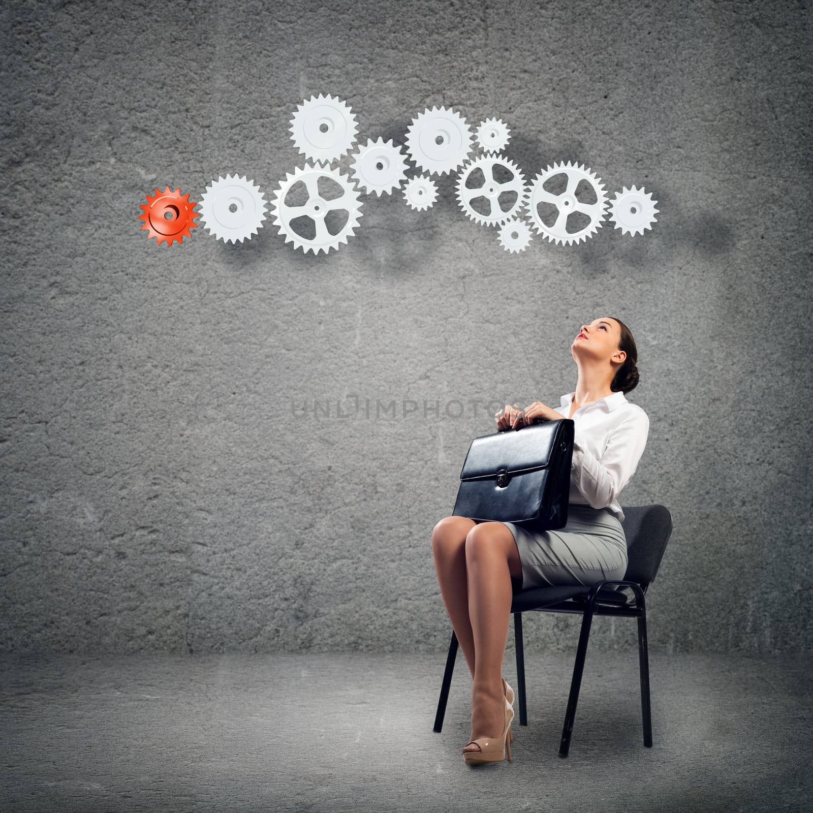 image of a beautiful young business woman sitting on a chair and looking at the gears on