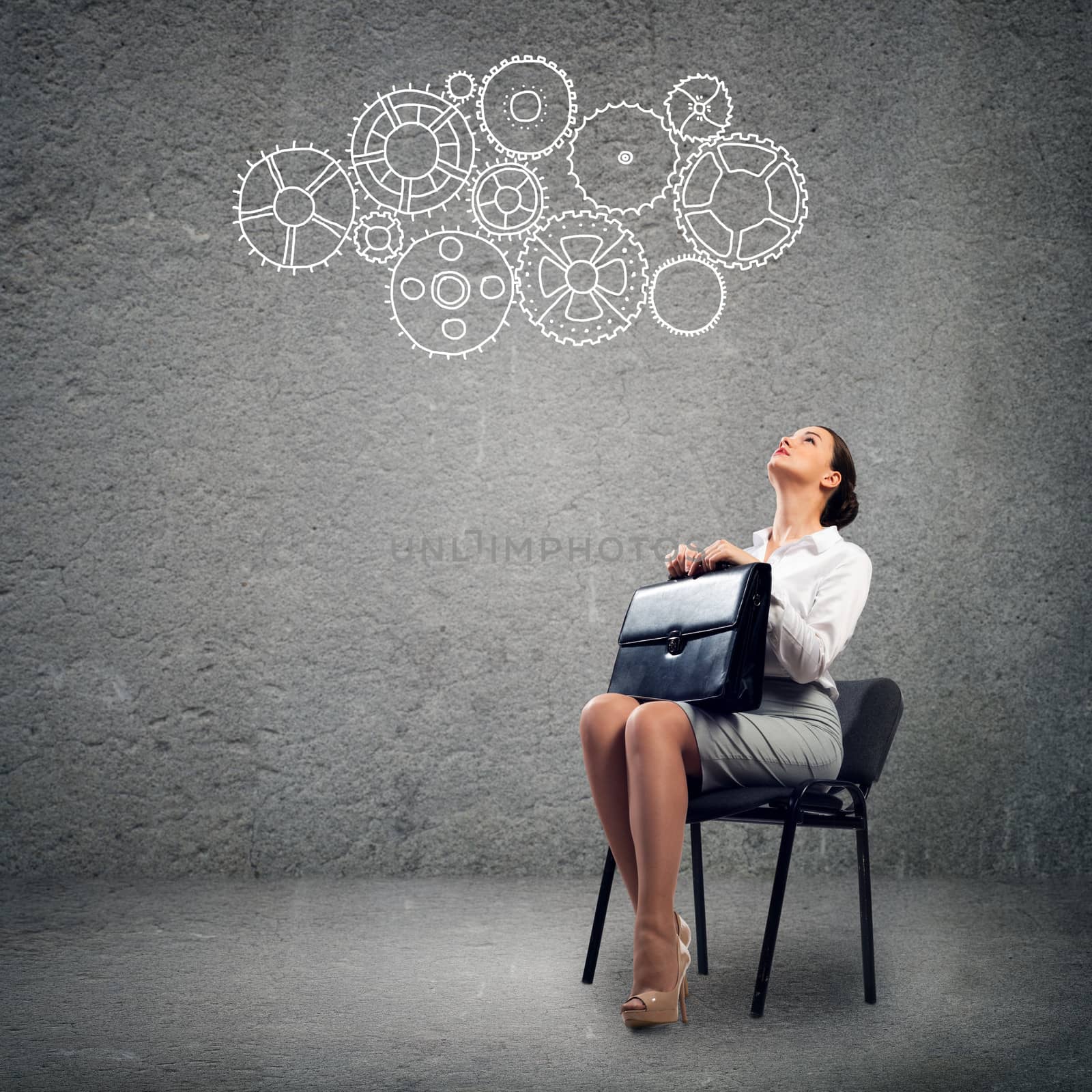 image of a beautiful young business woman sitting on a chair and looking at the gears on