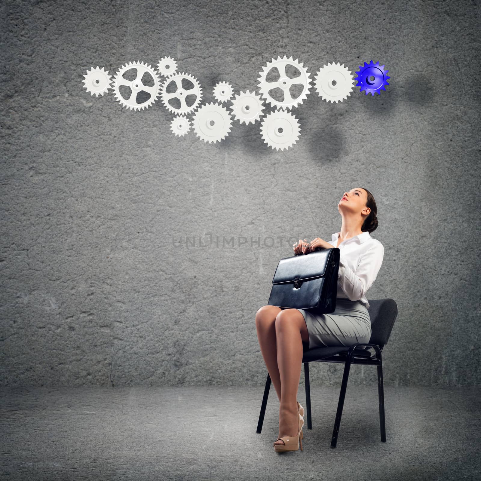 image of a beautiful young business woman sitting on a chair and looking at the gears on