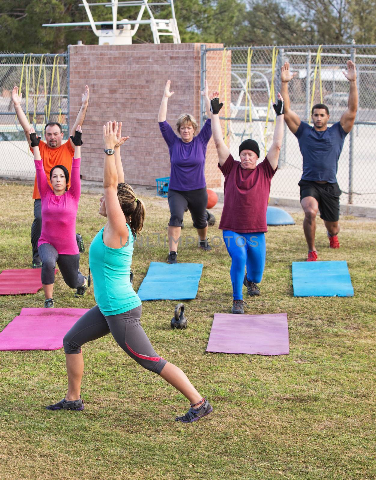 Mature adult boot camp exercise group stretching outdoors