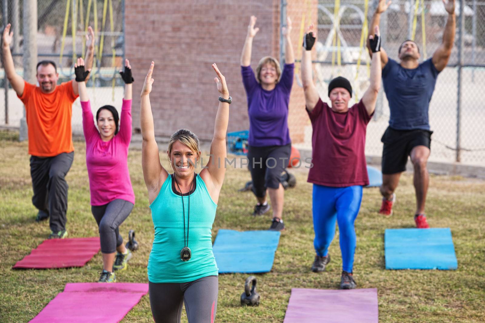 Group of active adults stretching outdoors with mats