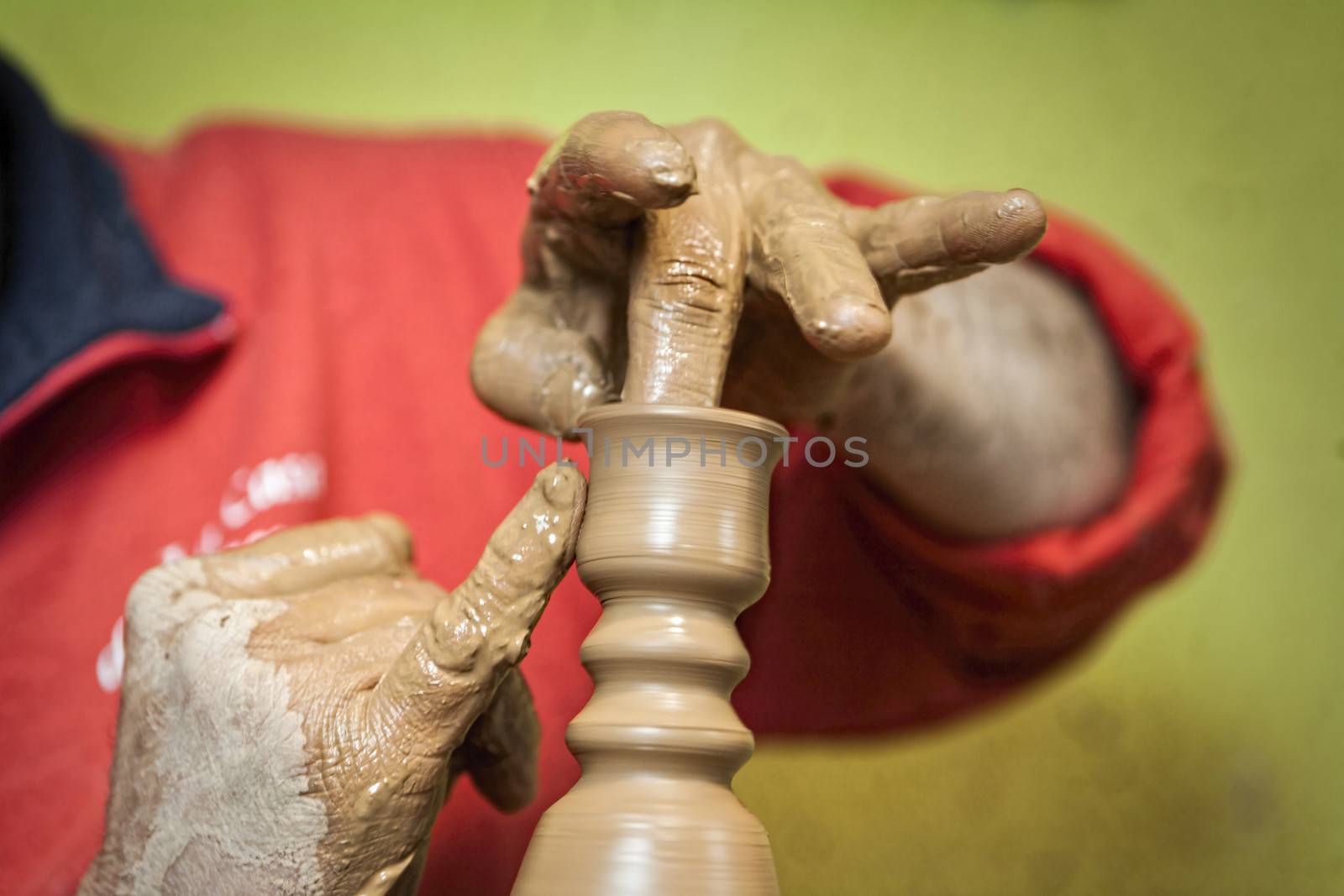 Potter making a humble candle holder of ceramics with their hand by digicomphoto
