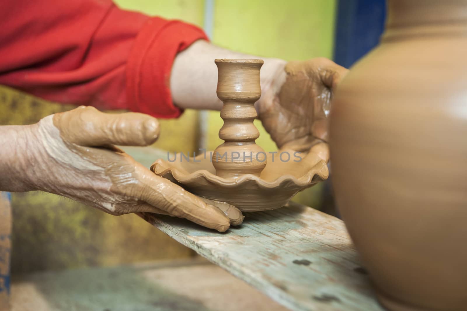 Potter by placing on a table of wood own candle holder of freshly made ceramic, clay pottery ceramics typical of Bailen, Jaen province, Andalucia, Spain