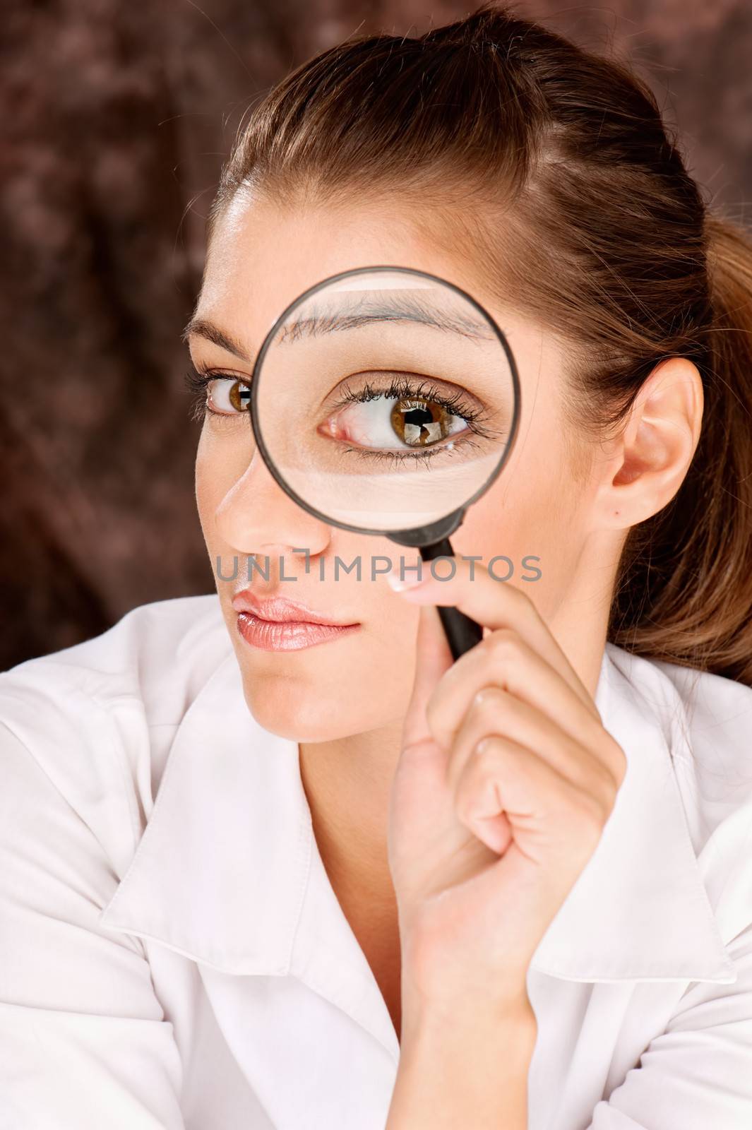 Pretty female researcher looking through magnifier glass