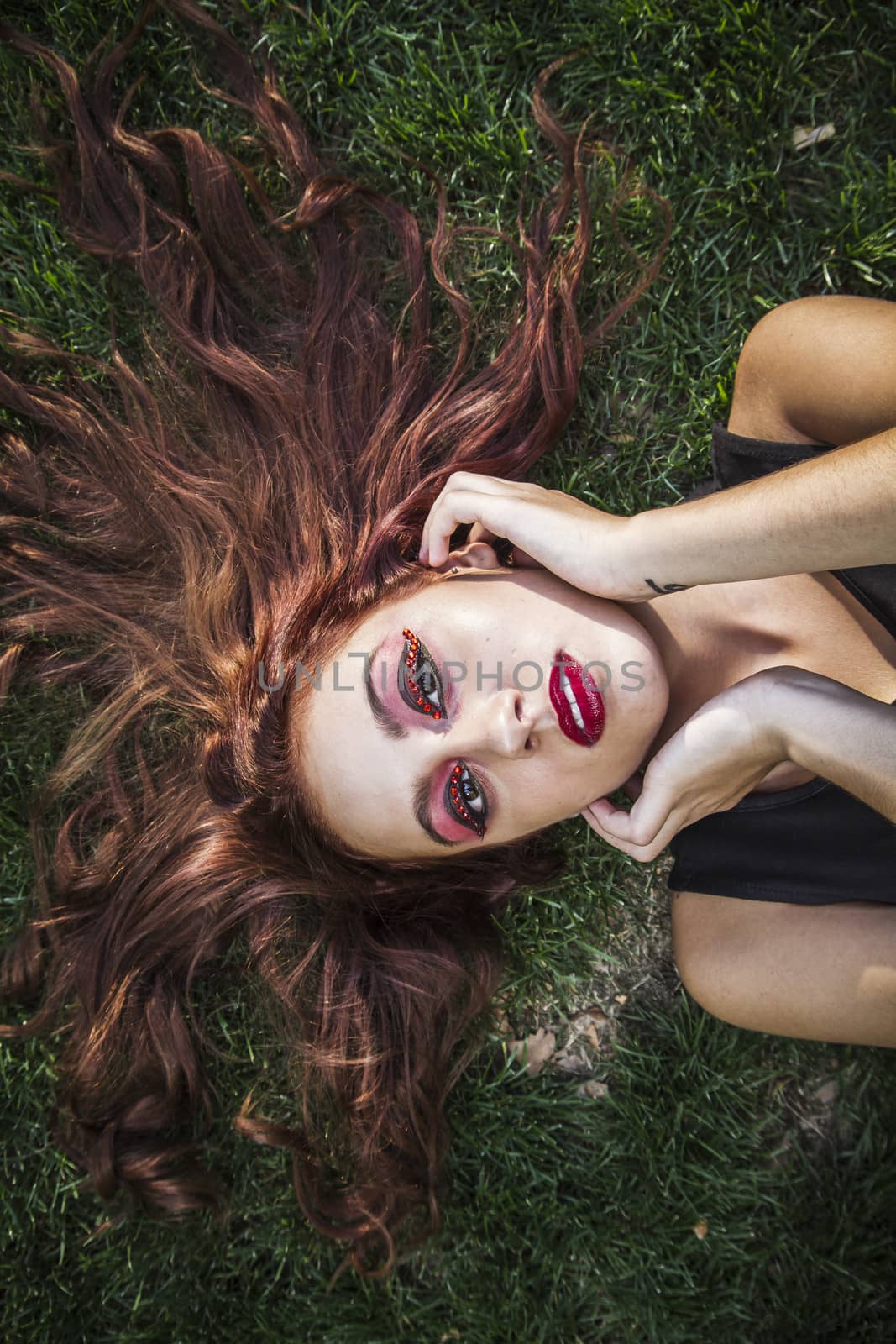 Side view of young woman sleeping on grass at park by FernandoCortes