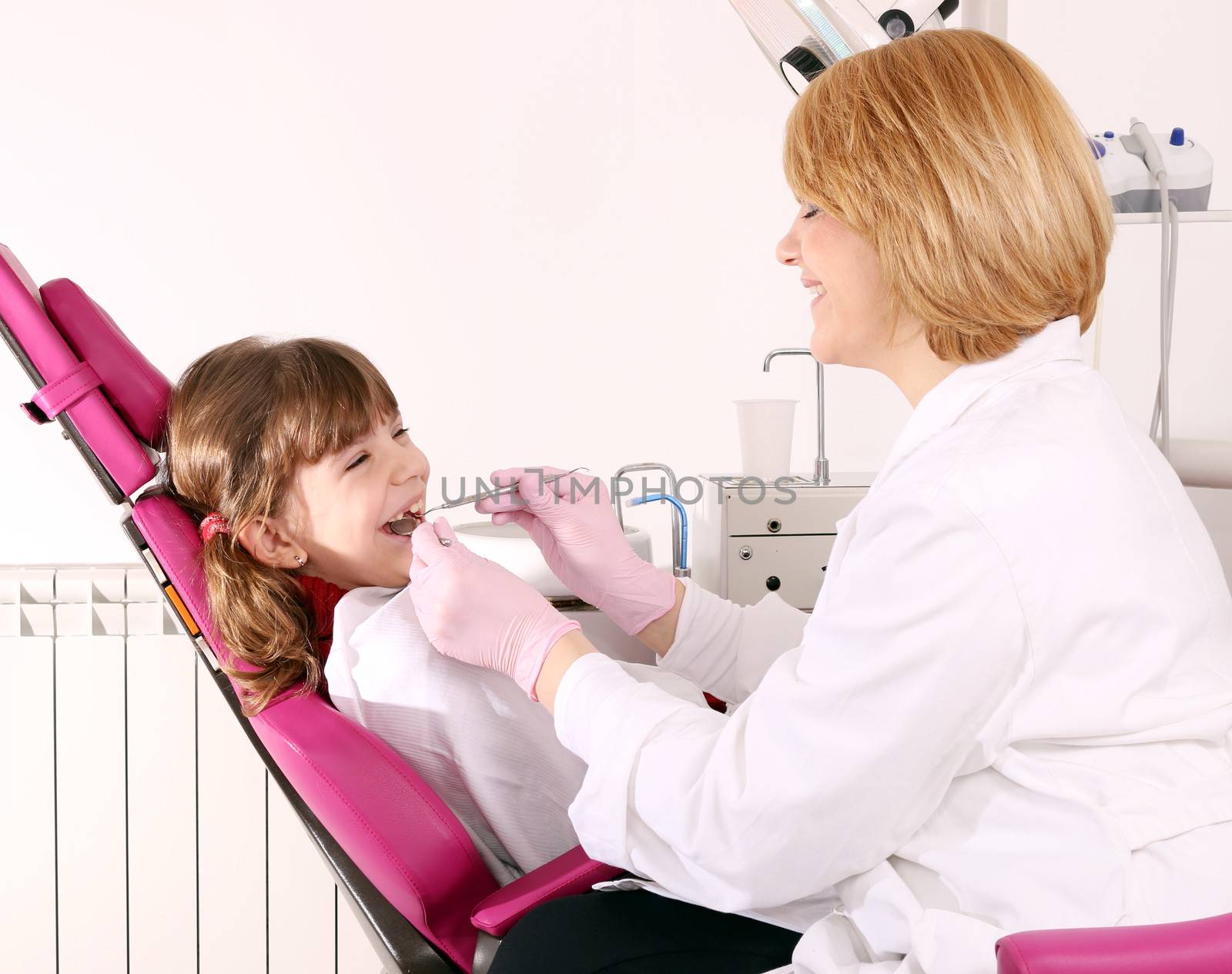 dentist and little girl patient dental exam by goce