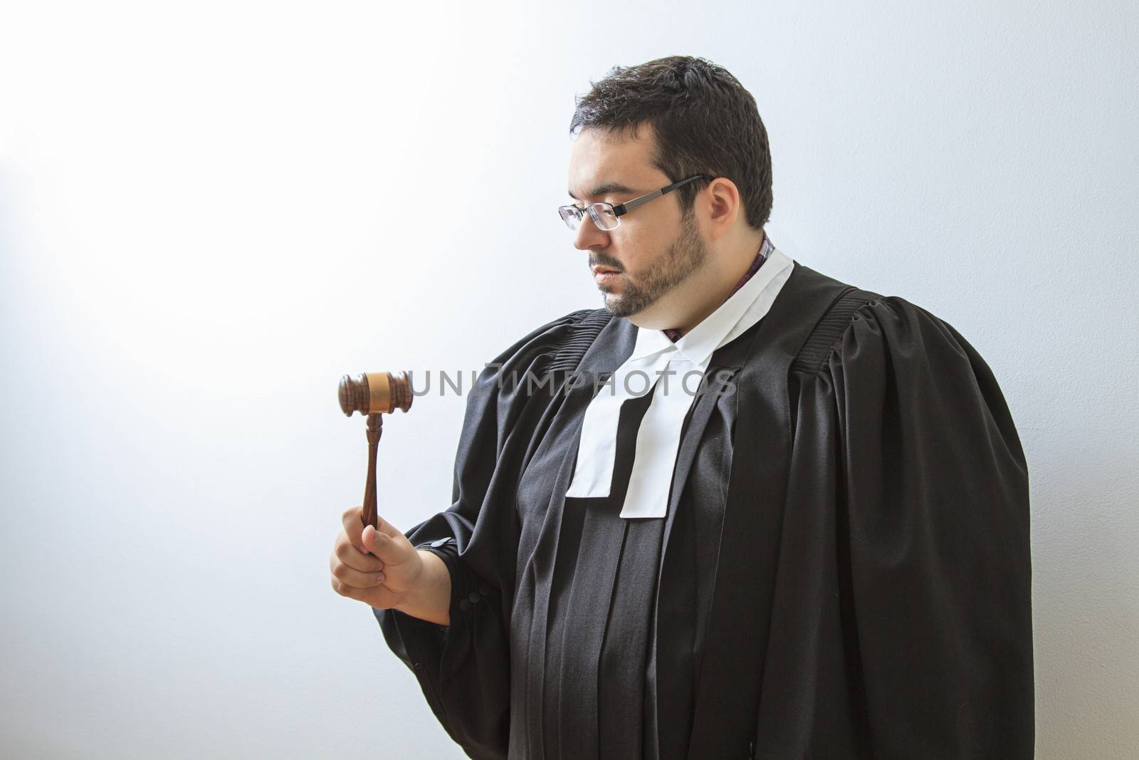 Man wearing a judge toga looking at a gavel