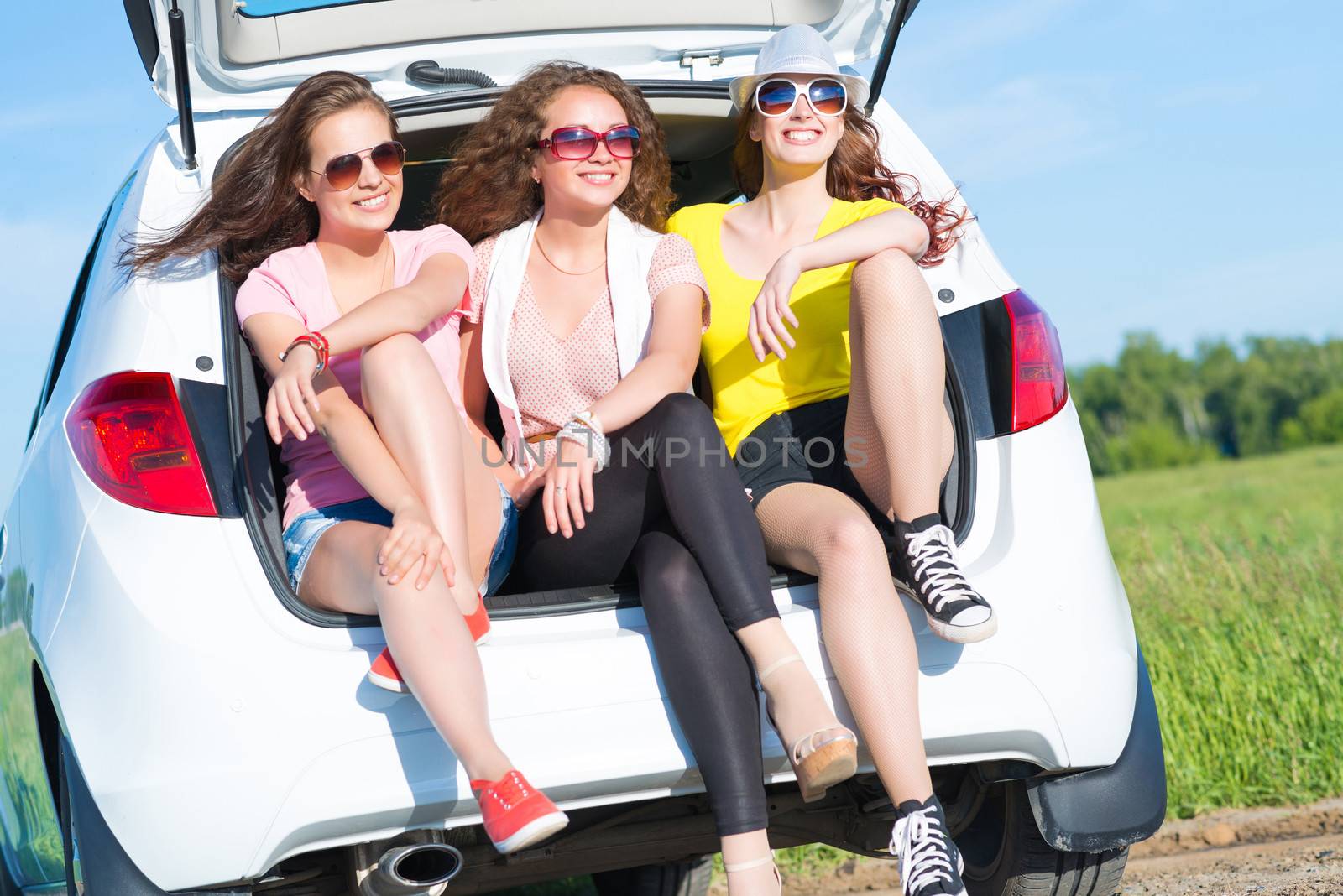 young attractive woman sitting in the open trunk of a new car, a summer road trip