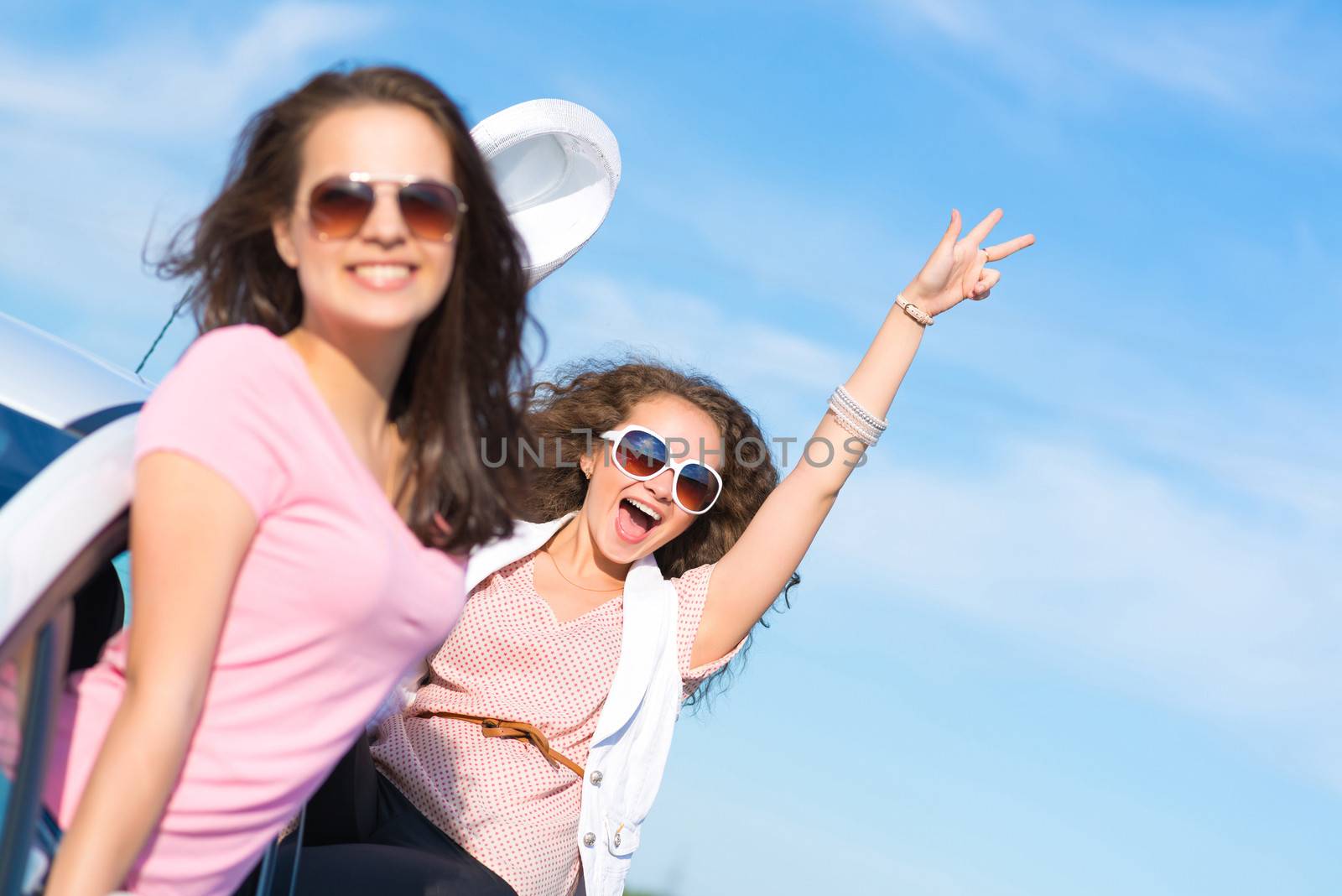 young attractive woman in sunglasses got out of the car window and laugh