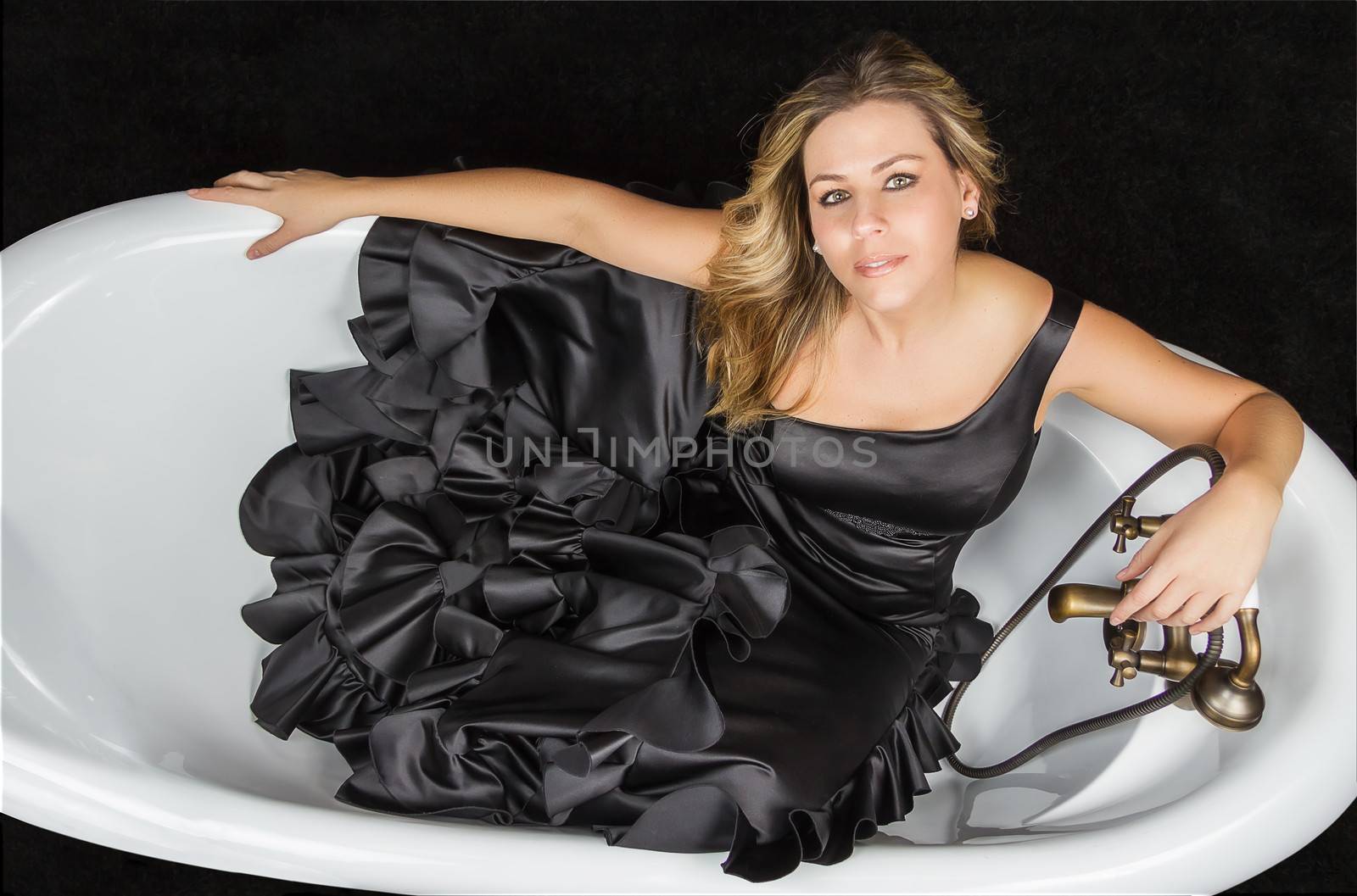 Portrait of beautiful fashion girl with black spanish flamenco dress posing in a vintage bathtub