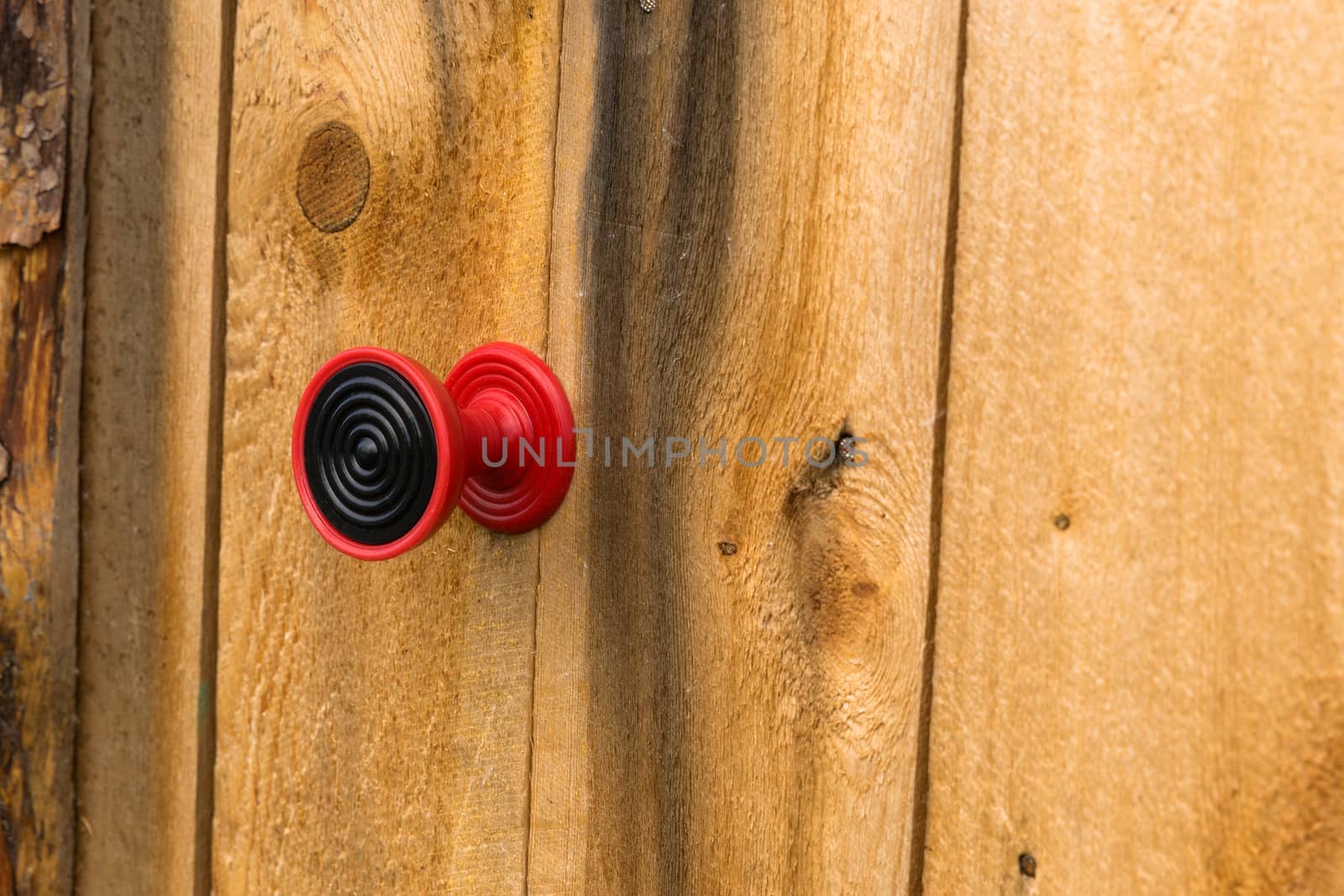 Red plastic handle on a wooden door