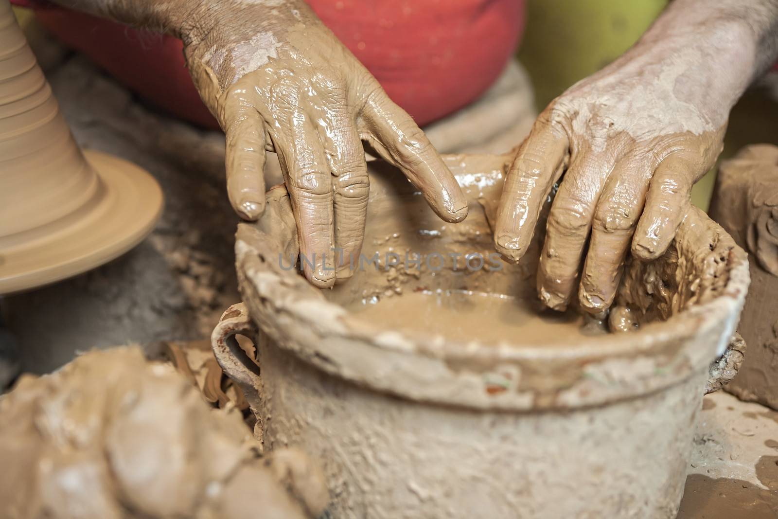 Detail of a potter's hands in a bucket of water by digicomphoto