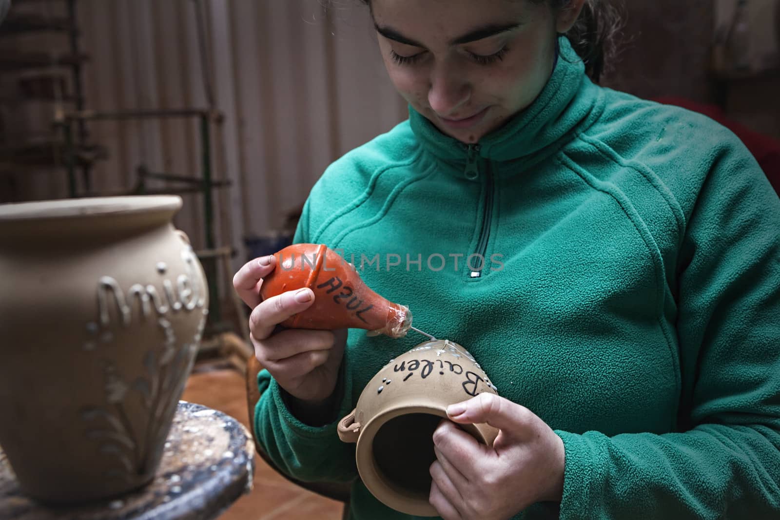 Potter decorating with enamel a ceramics piece before putting in the stove with branches drawings, clay pottery ceramics typical of Bailen, Jaen province, Andalucia, Spain