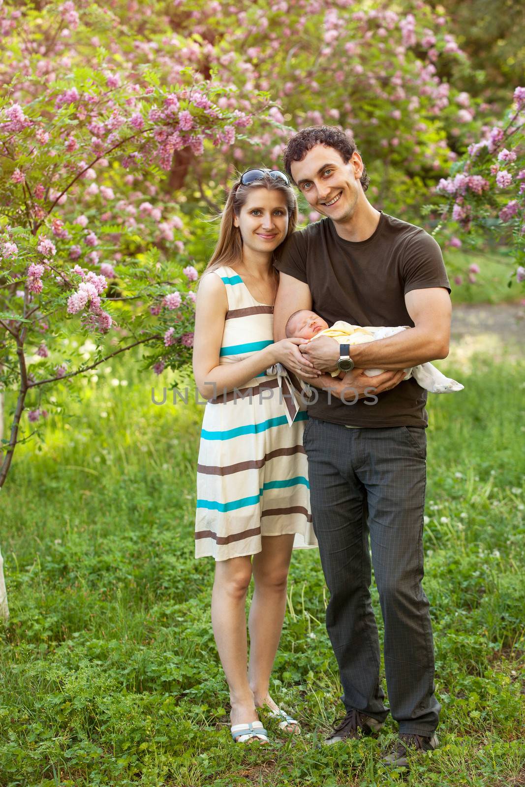 Happy young couple with newborn son outdoors in spring