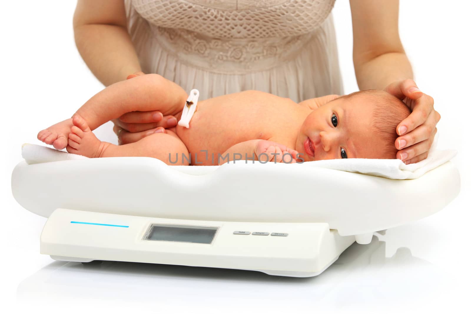Mother and her newborn baby on a weight scale over white background