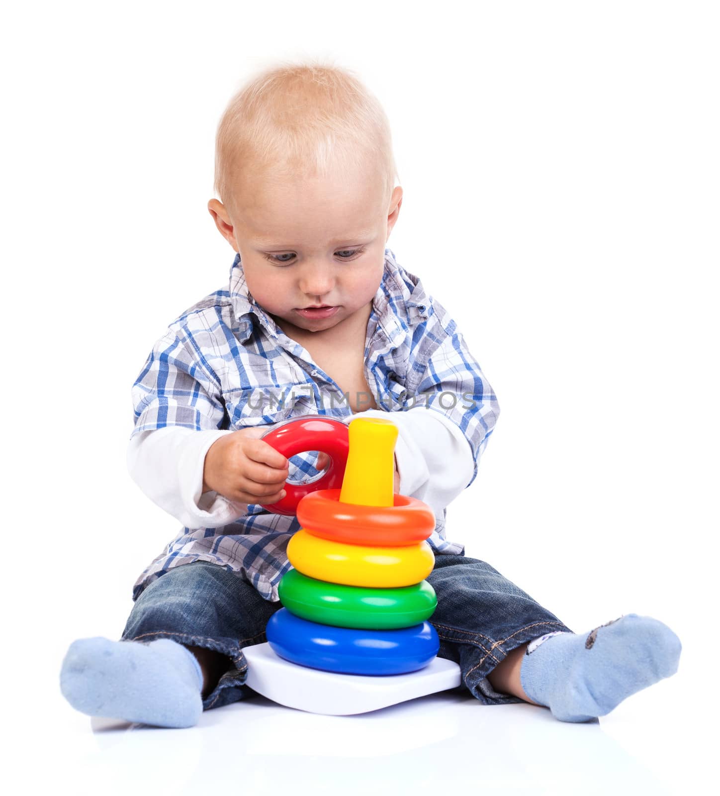 Cute little boy playing with pyramid toy over white background