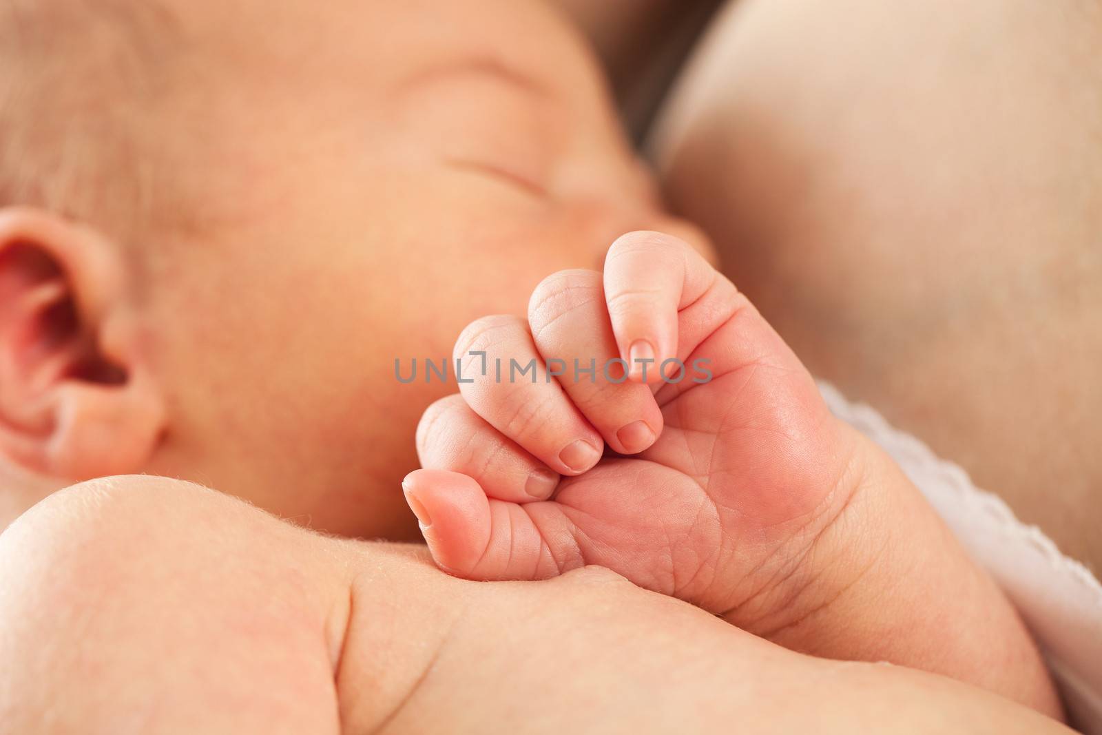 Newborn baby sleeping in mother's arm after breastfeeding