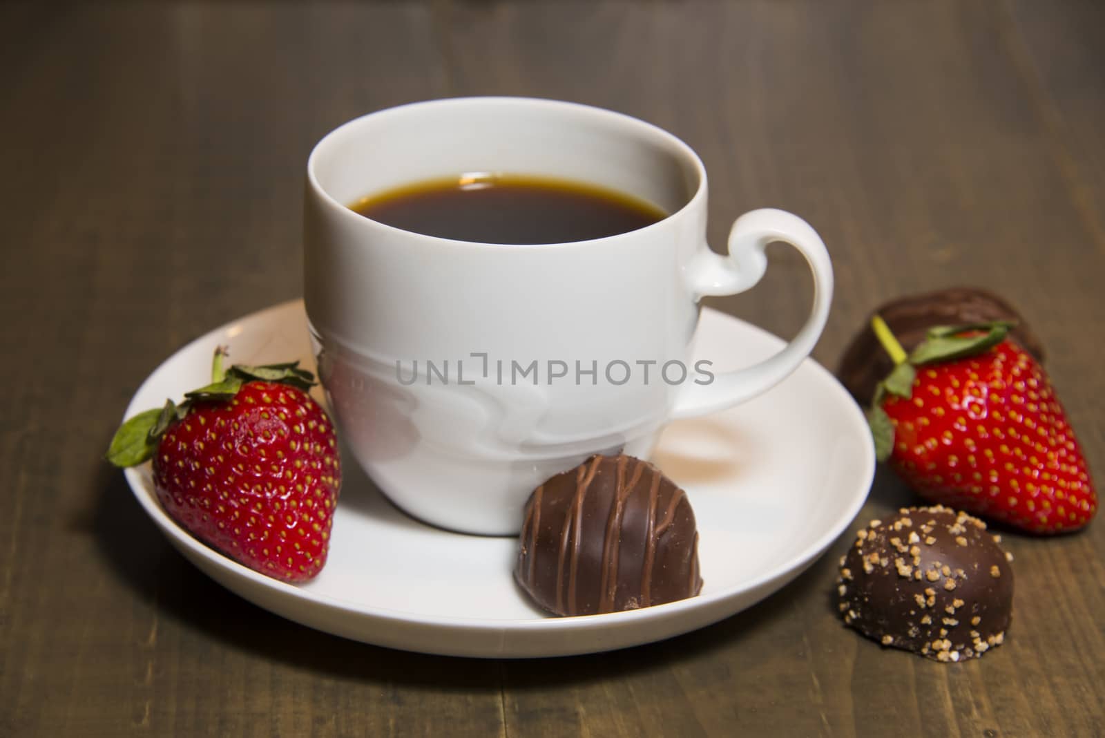 A cup of coffee in a porcelain, chololate and strawberries on a table