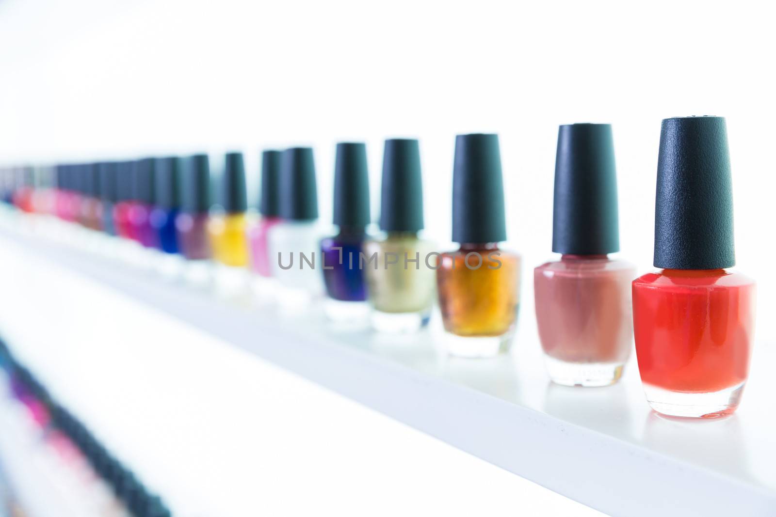 colorful nail polish colors in a row at nails saloon on white by lunamarina