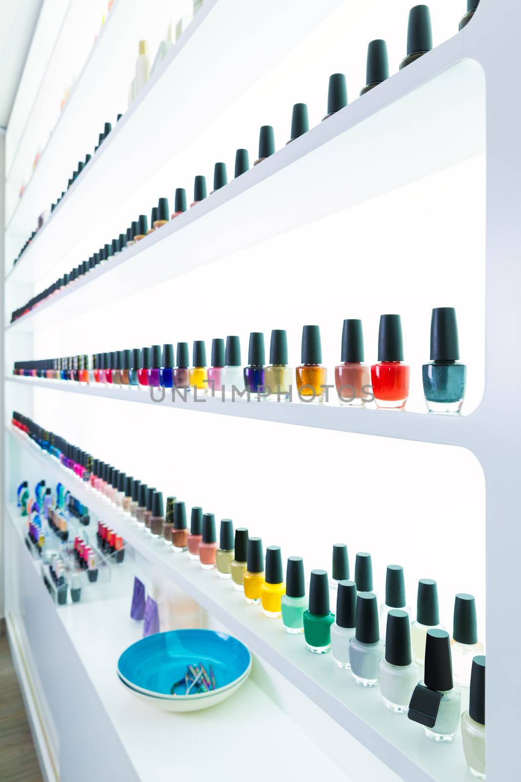 colorful nail polish colors in a row at nails saloon on white by lunamarina