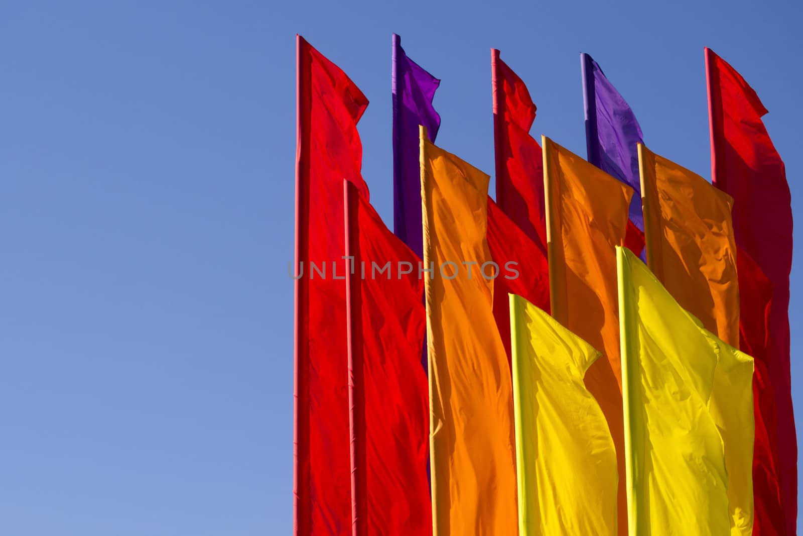 many color flags on the wind with clear blue sky behind